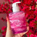 Hotflowers Blow Girl Intimate Aromatic Gel Strawberry & Cream 320ml – A hand gently holding the elegant square bottle of pink and white swirled gel against a soft, blurred pink floral background – Buy now at MKPBR.COM – Worldwide Shipping.