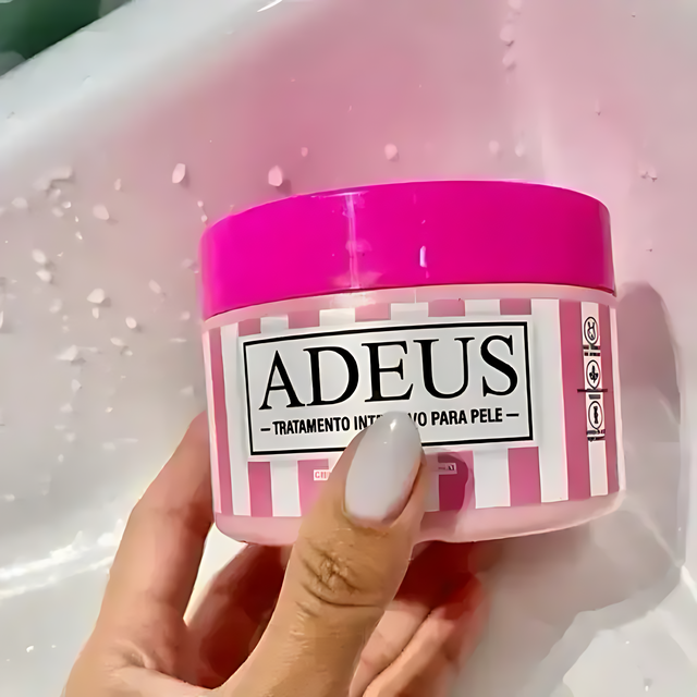 Adeus Cream cellulite and stretch mark cream in a pink and white striped jar held by a hand