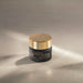 Closed jar of Boticário Botik Hyaluronic Acid and Caffeine Concentrated Eye Cream styled on a beige surface in soft sunlight, Brazilian dermocosmetic eye contour treatment 15 g – Buy now at MKPBR.COM – Worldwide Shipping