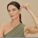 Model applying a drop of Boticário Botik Peptídeos Pró-Elastina Facial Serum to her cheek with the glass dropper, Brazilian skincare routine – Buy now at MKPBR.COM – Worldwide Shipping
