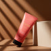 O Boticário Coffee Woman Unique Brazilian body lotion 200 ml tube leaning on a beige block in warm light and shadow – Buy now at MKPBR.COM – Worldwide Shipping