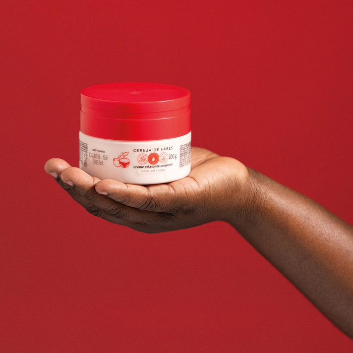 Closed 200 g jar of Boticário Cuide-se Bem Cereja de Fases relaxing body cream resting on an open hand as a size reference against a red backdrop – Buy now at MKPBR.COM – Worldwide Shipping