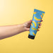 Hand holding the O Boticário Cuide-se Bem Feira Banana Shampoo 230 ml tube against a yellow background, showing the flip-top cap and tube size – Buy now at MKPBR.COM – Worldwide Shipping