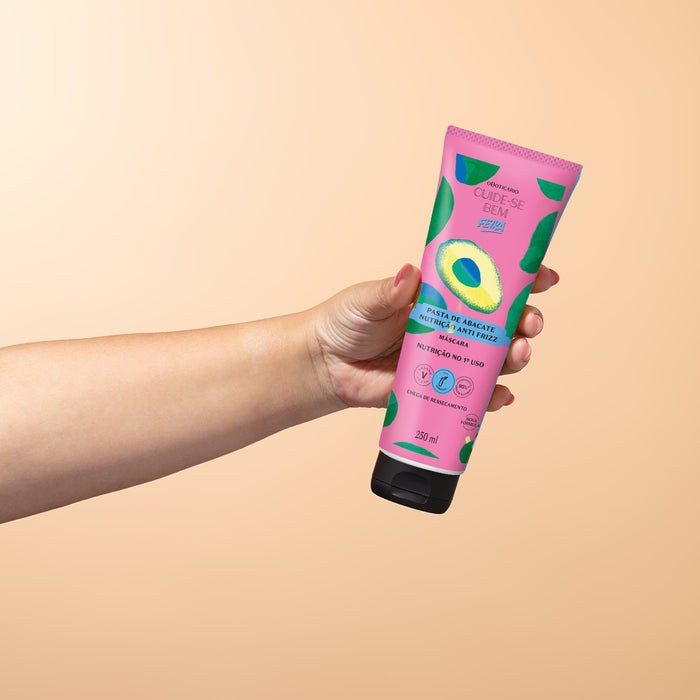 Hand holding the Boticário Cuide-se Bem Feira Pasta de Abacate avocado hair mask 250 ml tube against a peach gradient background – Buy now at MKPBR.COM – Worldwide Shipping
