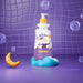 Boticário Dr. Botica Poção das Bolhas kids body wash 400 ml bottle standing on a blue foam cloud among soap bubbles in a playful purple bath-time scene – Buy now at MKPBR.COM – Worldwide Shipping