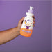 Hand holding the ergonomic 350 ml Boticário Dr. Botica kids curl defining cream bottle, showing the accessible packaging and colour-coded pump – Buy now at MKPBR.COM – Worldwide Shipping