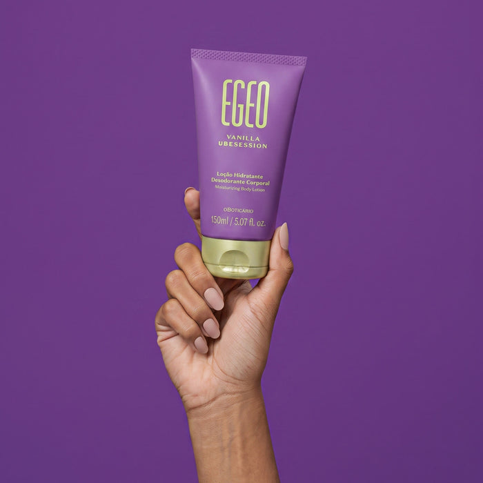 Hand holding the 5.07 fl oz Boticário Egeo Vanilla Ubesession deodorant body lotion tube against a purple background, showing the travel-friendly size – Buy now at MKPBR.COM – Worldwide Shipping
