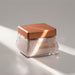 Angled lifestyle shot of Boticário Elysée Satin Body Cream 250 g jar in warm sunlight showing the copper cap and satin cream texture – Buy now at MKPBR.COM – Worldwide Shipping