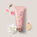 Floratta Rose Bouquet body lotion tube by O Boticário in a flat lay with pink roses, a white gardenia and a sliced pear illustrating the floral fragrance notes – Buy now at MKPBR.COM – Worldwide Shipping
