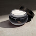O Boticário Her Code Velvet Body Cream 250 g jar with the lid off, showing the dense white cream in natural sunlight – Buy now at MKPBR.COM – Worldwide Shipping