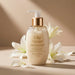 Boticário Lily Acetinado Satin Conditioner 250 ml styled with fresh white lily flowers on a beige backdrop, highlighting the floral Lily fragrance – Buy now at MKPBR.COM – Worldwide Shipping