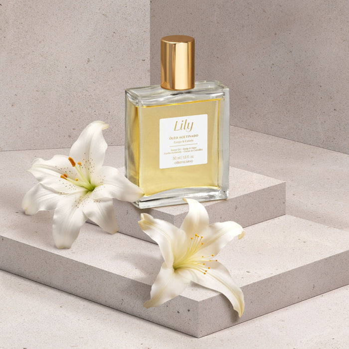 Boticário Lily Satin Multipurpose Body & Hair Oil 50 ml bottle styled on a stone plinth with fresh white lily flowers, Brazilian body and hair oil – Buy now at MKPBR.COM – Worldwide Shipping