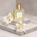 Boticário Lily Satin Multipurpose Body & Hair Oil 50 ml bottle styled on a stone plinth with fresh white lily flowers, Brazilian body and hair oil – Buy now at MKPBR.COM – Worldwide Shipping