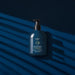 O Boticário Malbec Deodorant Body Lotion 200 ml bottle styled on a deep navy backdrop with shadow play, Brazilian grape seed body moisturizer for men – Buy now at MKPBR.COM – Worldwide Shipping
