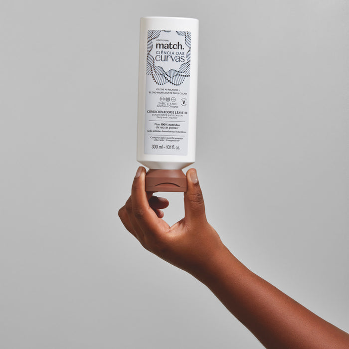 Hand holding the Boticario Match Ciencia das Curvas Conditioner and Leave-In 300 ml bottle upside down against a grey background, showing bottle size and flip-top cap – Buy now at MKPBR.COM – Worldwide Shipping