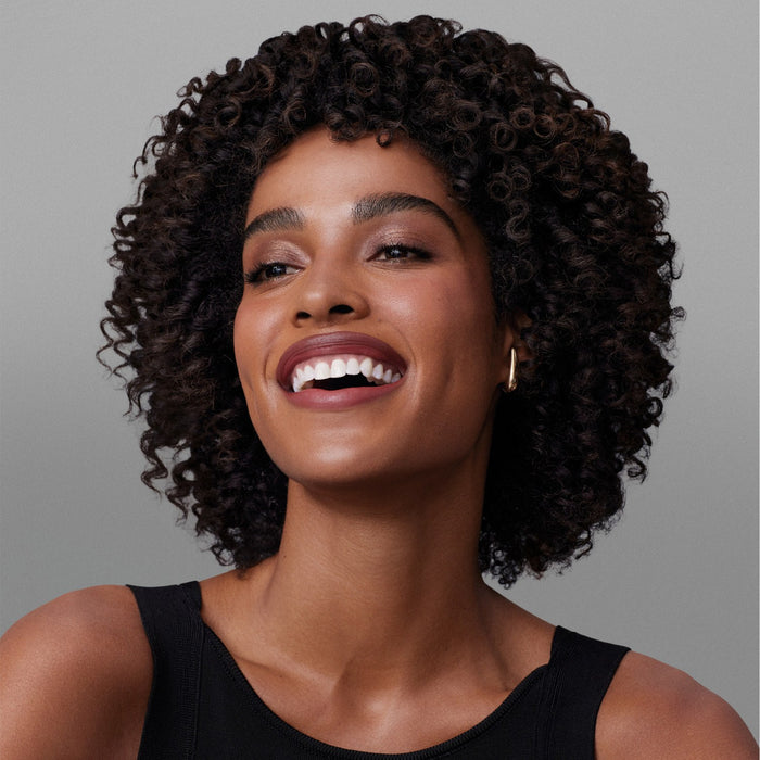 Smiling model with soft defined curls showcasing results of Boticário Match Deep Nutrition Brazilian hair mask – Buy now at MKPBR.COM – Worldwide Shipping