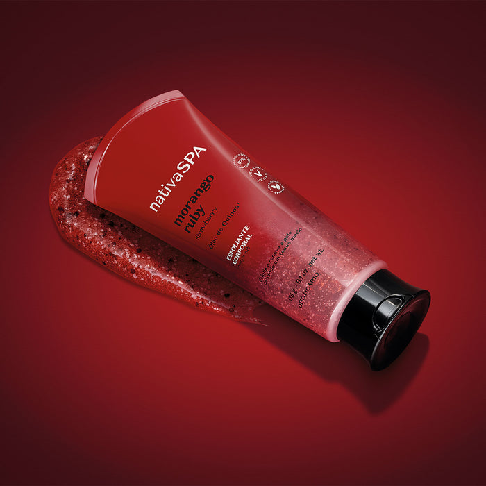 Nativa SPA Morango Ruby Body Scrub tube tilted with exfoliating gel spilling out on a red studio backdrop – Buy now at MKPBR.COM – Worldwide Shipping