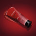 Nativa SPA Morango Ruby Body Scrub tube tilted with exfoliating gel spilling out on a red studio backdrop – Buy now at MKPBR.COM – Worldwide Shipping