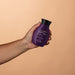 Hand holding the Boticário Nativa SPA Orquídea Noire body oil bottle against a warm beige background, showing its compact 200 ml size – Buy now at MKPBR.COM – Worldwide Shipping