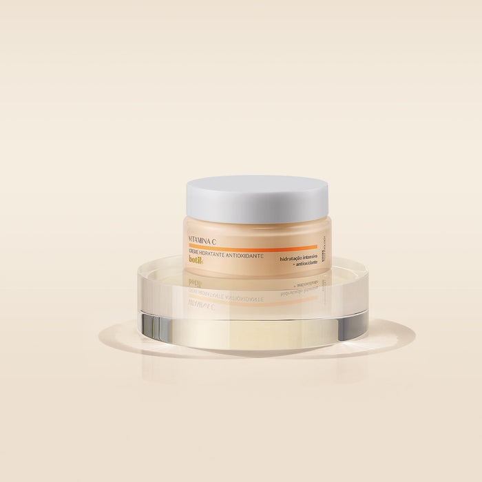O Boticário Botik Vitamina C Antioxidant Face Moisturizer 50 g jar displayed on a clear acrylic pedestal against a warm beige background – Buy now at MKPBR.COM – Worldwide Shipping