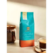Orfeu Arara Whole Bean Coffee – A freshly brewed cup of Arara coffee with the whole bean bag in the background, suggesting quality from bean to cup. – Buy now at MKPBR.COM – Worldwide Shipping