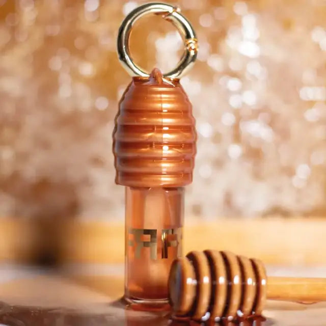 Fran by Franciny Ehlke Lip Honey Lip Gloss in an artistic concept shot, highlighting its honeycomb design and shine – Buy now at MKPBR.COM – Worldwide Shipping