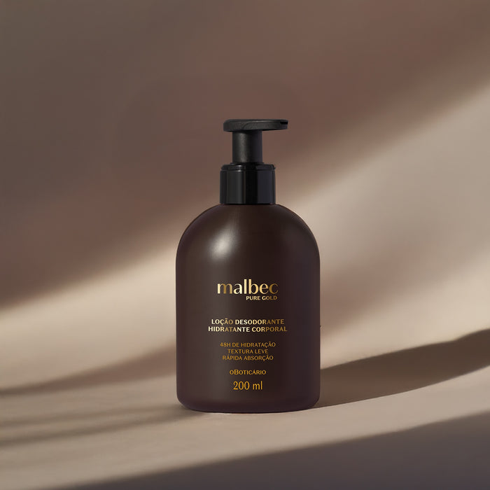 Boticário Malbec Pure Gold deodorant body lotion pump bottle photographed in warm directional light on a neutral beige backdrop – Buy now at MKPBR.COM – Worldwide Shipping
