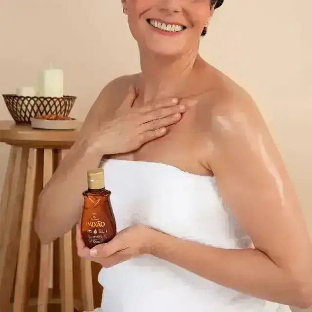 Woman applying Paixão Avelã (Hazelnut) body oil to shoulder with a dewy finish. Buy now at MKPBR.COM – Worldwide Shipping