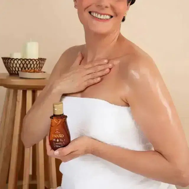 Woman applying Paixão Avelã (Hazelnut) body oil to shoulder with a dewy finish. Buy now at MKPBR.COM – Worldwide Shipping