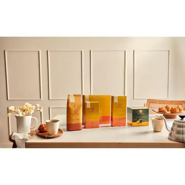 Orfeu Bourbon Amarelo Espresso Capsules – 100% Arabica, Medium-Light Roast – 3.53 oz (100g) – A warm, inviting image showcasing various Orfeu Bourbon coffee products, including cups and a coffee pot, setting a lifestyle scene. – Buy now at MKPBR.COM – Worldwide Shipping