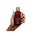 Paixão Flor de Baunilha body oil 100 mL held in hand, size reference, magenta bottle with gold cap. Buy now at MKPBR.COM – Worldwide Shipping