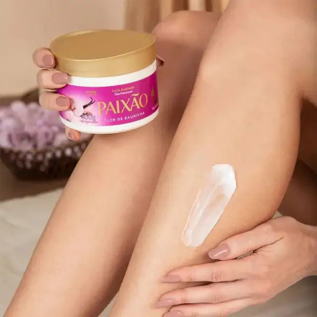 Woman applying Paixão Flor de Baunilha hydrating satin body lotion with almond oil to her leg for a soft, silky finish. Buy now at MKPBR.COM – Worldwide Shipping