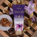 Paixão Irresistível Flor de Lis ultra‑creamy body lotion tube in flat lay with almonds and purple flowers on rustic wood. Buy now at MKPBR.COM – Worldwide Shipping