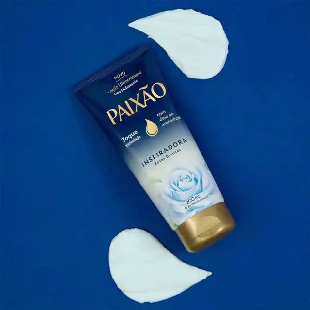 Front hero of Paixão Rosas Brancas lotion on vibrant blue background with white lotion smears showing texture. Buy now at MKPBR.COM – Worldwide Shipping