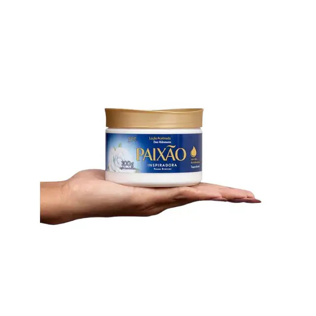 Hand holding a closed 300g jar of Paixão Inspiradora Rosas Brancas hydrating body lotion on a white background. — Buy now at MKPBR.COM – Worldwide Shipping