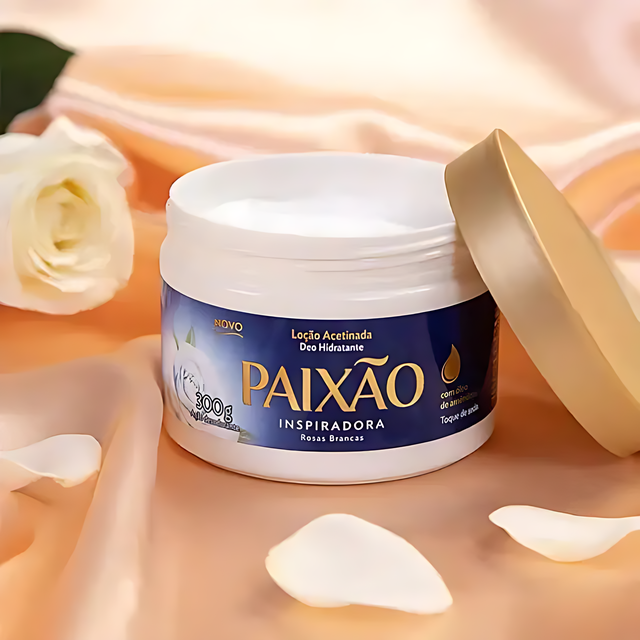 Open jar of Paixão Inspiradora Rosas Brancas hydrating lotion on peach satin with a white rose and petals. — Buy now at MKPBR.COM – Worldwide Shipping
