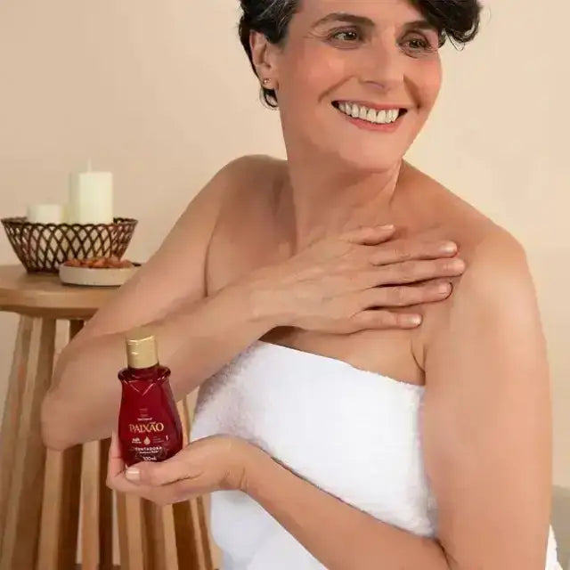 Woman applying Paixão Tempting Ruby Plum body oil on shoulder. Buy now at MKPBR.COM – Worldwide Shipping