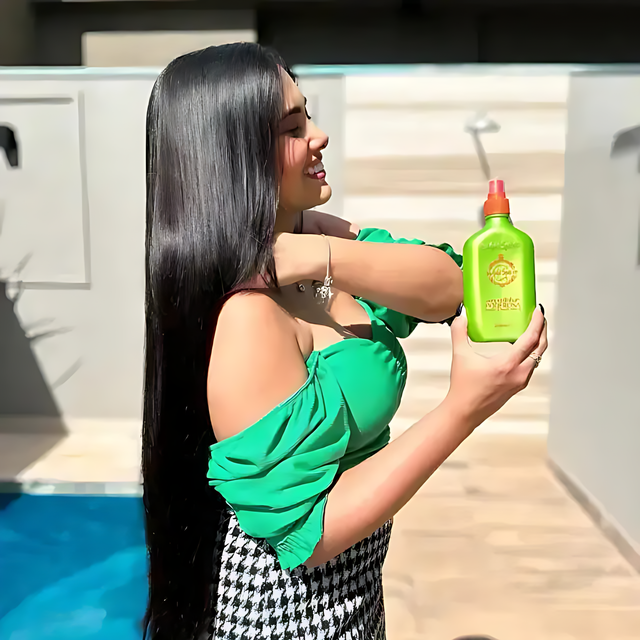 Smiling model in green top holding Gold Spell Receitinha Poderosa hair tonic 250ml outdoors - Buy now at MKPBR.COM - Worldwide Shipping