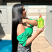 Smiling model in green top holding Gold Spell Receitinha Poderosa hair tonic 250ml outdoors - Buy now at MKPBR.COM - Worldwide Shipping