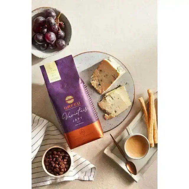 Orfeu Japy Whole Bean Coffee – A lifestyle flat lay featuring the Orfeu Japy Whole Bean Coffee package, a brewed cup, grapes, and cheese, creating an inviting scene. – Buy now at MKPBR.COM – Worldwide Shipping